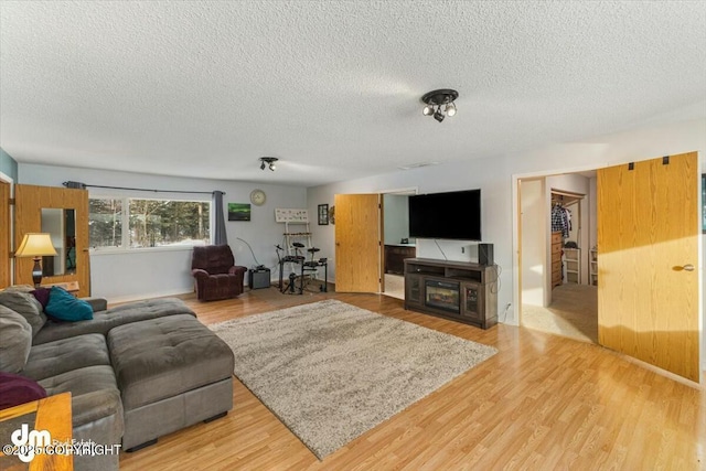 living room with a textured ceiling and light wood-type flooring