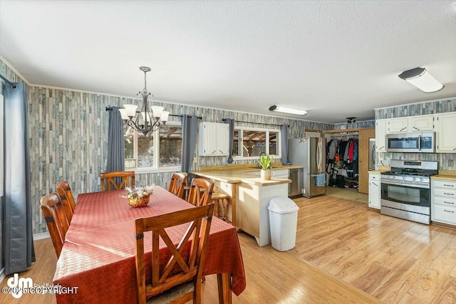 dining space with a textured ceiling, light hardwood / wood-style floors, and a chandelier