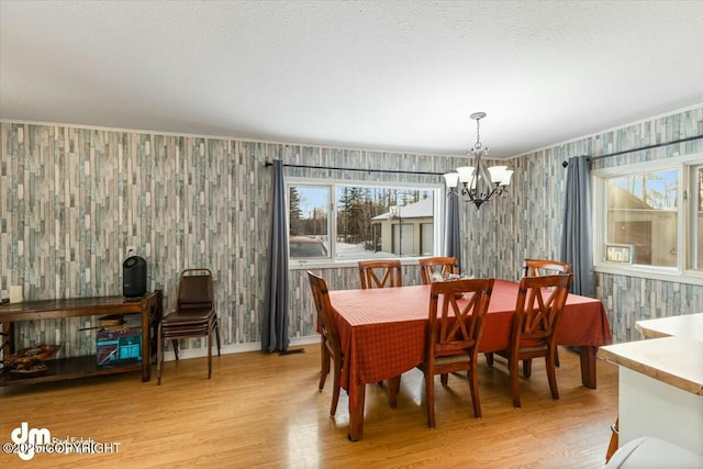 dining room with a textured ceiling, an inviting chandelier, and light hardwood / wood-style flooring