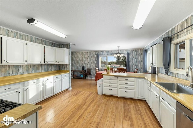 kitchen featuring sink, stainless steel dishwasher, white cabinets, and kitchen peninsula