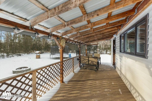 snow covered deck featuring a trampoline and an outdoor fire pit