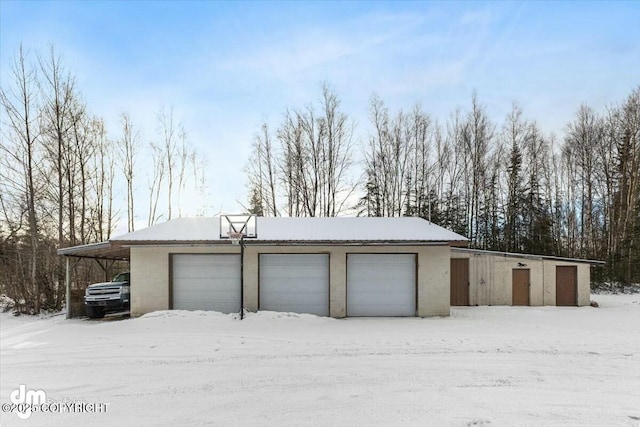 snow covered garage featuring a carport