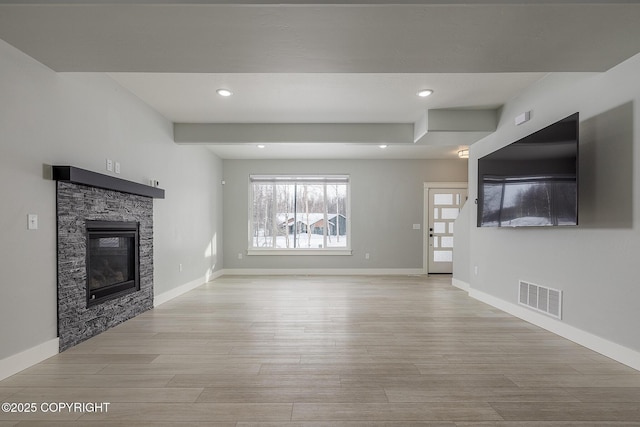 unfurnished living room featuring a fireplace and light hardwood / wood-style flooring