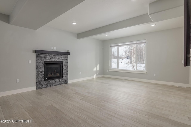 unfurnished living room with a fireplace, beamed ceiling, and light wood-type flooring