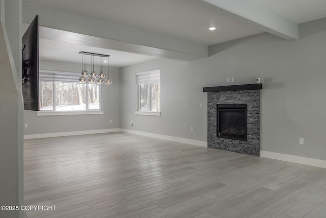 unfurnished living room featuring beam ceiling, a fireplace, and light hardwood / wood-style floors