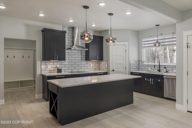 kitchen featuring a kitchen island, dishwasher, sink, hanging light fixtures, and wall chimney range hood