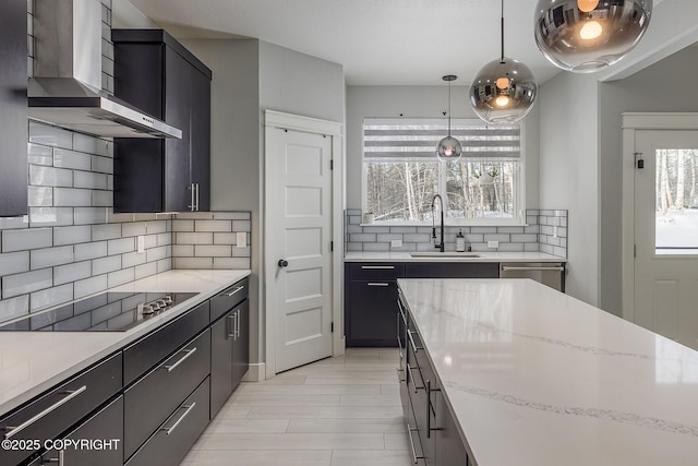 kitchen featuring wall chimney exhaust hood, sink, light stone counters, hanging light fixtures, and black electric stovetop