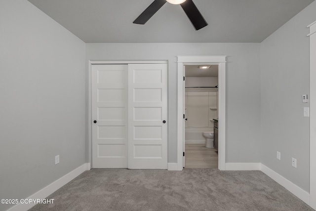 unfurnished bedroom featuring ensuite bathroom, light carpet, ceiling fan, and a closet