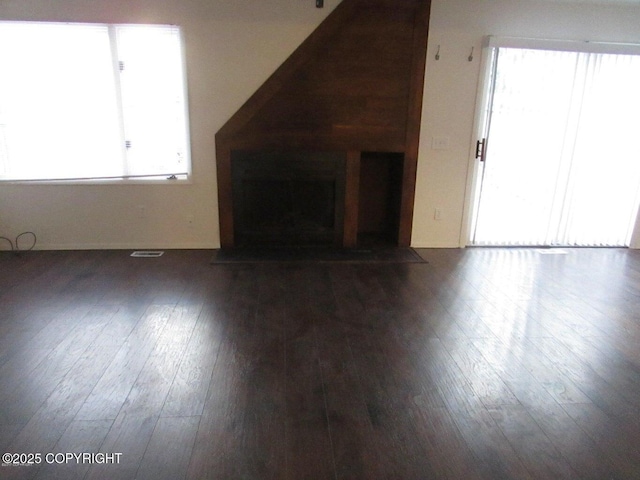 unfurnished living room with a wealth of natural light and dark hardwood / wood-style floors