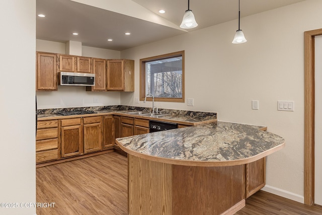 kitchen featuring black appliances, sink, hanging light fixtures, kitchen peninsula, and light hardwood / wood-style flooring