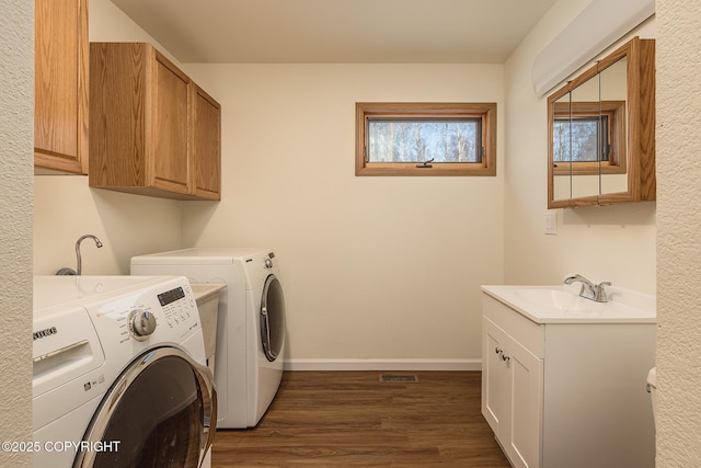 clothes washing area with cabinets, dark hardwood / wood-style flooring, washer and clothes dryer, and sink