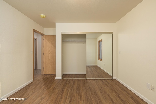 unfurnished bedroom featuring dark hardwood / wood-style floors and a closet