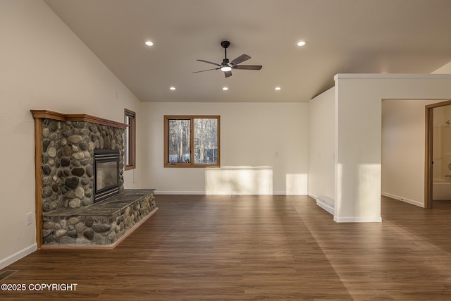 unfurnished living room with ceiling fan, a stone fireplace, lofted ceiling, and dark hardwood / wood-style flooring