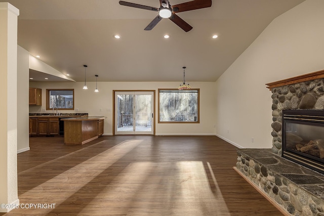 unfurnished living room with ceiling fan, dark hardwood / wood-style flooring, sink, and a stone fireplace