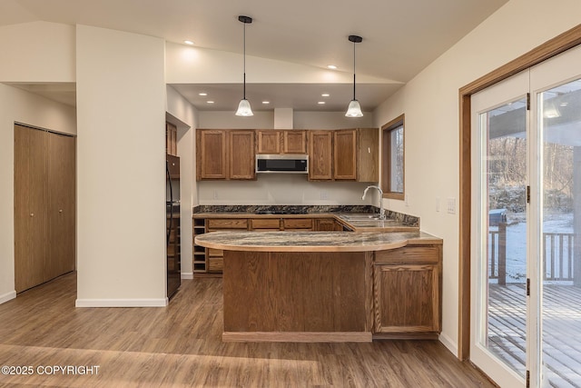 kitchen featuring lofted ceiling, hanging light fixtures, kitchen peninsula, and light wood-type flooring