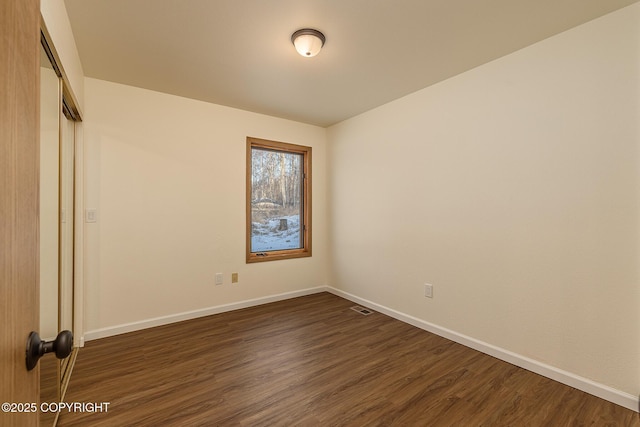 unfurnished room with dark wood-type flooring