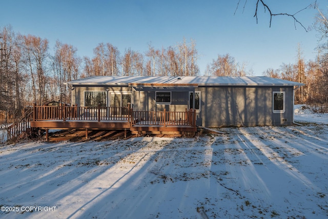 snow covered rear of property with a wooden deck