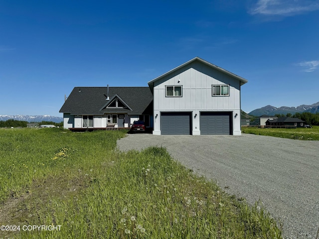 view of front of house with a garage, board and batten siding, gravel driveway, and a mountain view