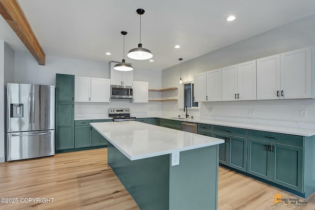 kitchen with light wood finished floors, pendant lighting, stainless steel appliances, green cabinets, and a sink