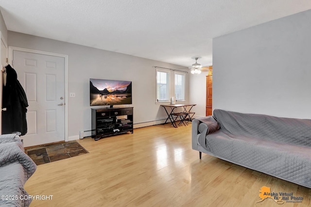 living room with a baseboard radiator, light hardwood / wood-style floors, and a textured ceiling