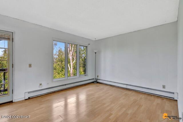 7750 Boundary Ave # A3, Anchorage, AK 99504 - empty room featuring a baseboard heating unit, wood finished floors, and plenty of natural light