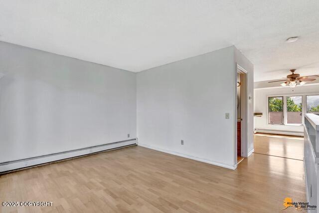 7750 Boundary Ave # A3, Anchorage, AK 99504 - unfurnished room featuring a baseboard radiator, wood finished floors, and a ceiling fan