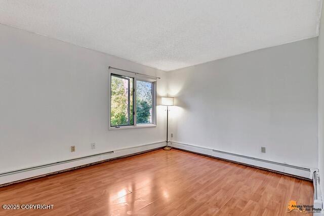 7750 Boundary Ave # A3, Anchorage, AK 99504 - spare room with wood finished floors and a baseboard radiator