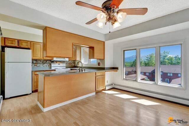 7750 Boundary Ave # A3, Anchorage, AK 99504 - kitchen featuring white appliances, light wood-type flooring, baseboard heating, a ceiling fan, and a peninsula