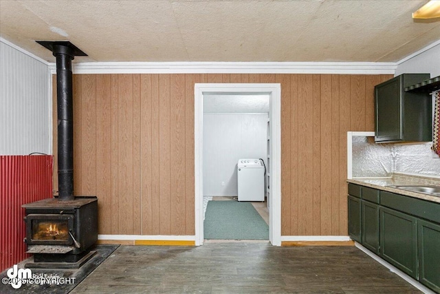 kitchen featuring washer / dryer, wood walls, a wood stove, dark hardwood / wood-style floors, and green cabinets