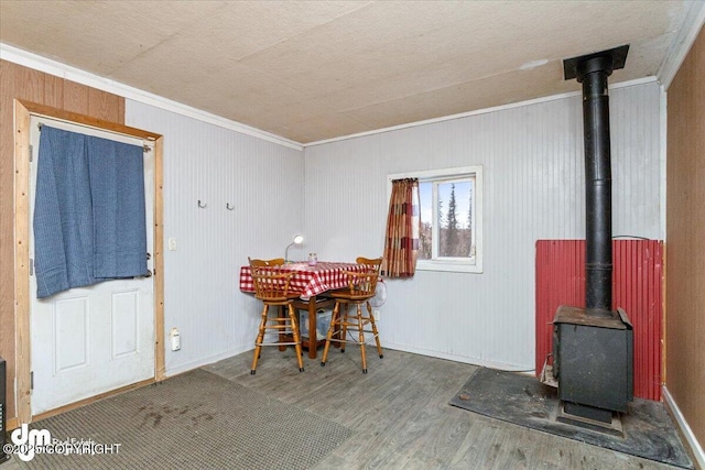 dining space featuring hardwood / wood-style flooring, ornamental molding, and a wood stove