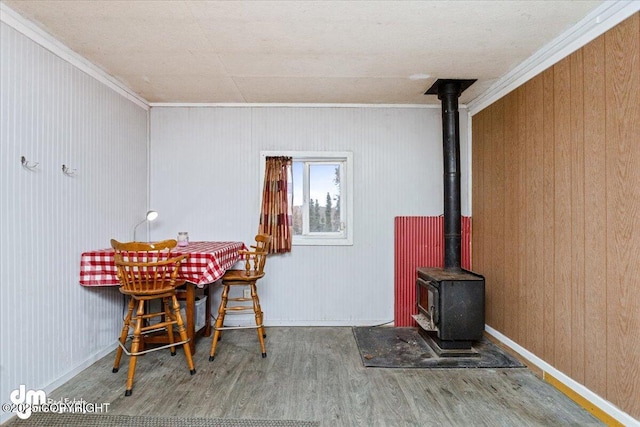 unfurnished dining area featuring hardwood / wood-style floors, ornamental molding, and a wood stove