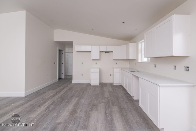 kitchen featuring white cabinetry, sink, light hardwood / wood-style flooring, and lofted ceiling