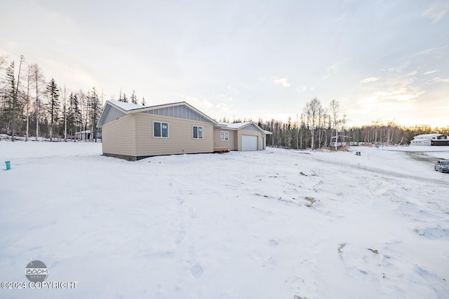 snow covered back of property featuring a garage