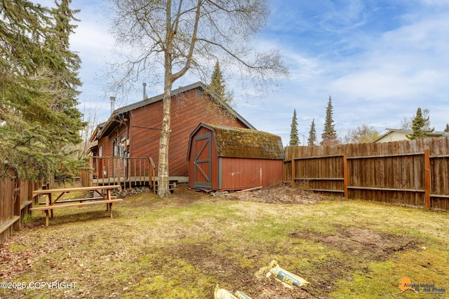 view of yard with a fenced backyard, a storage unit, an outdoor structure, and a wooden deck
