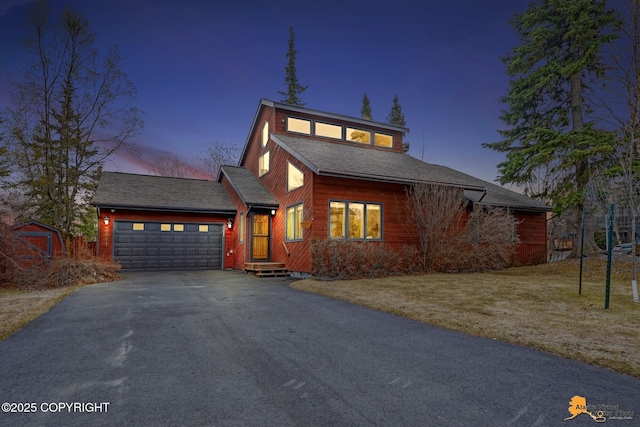 traditional-style home with an attached garage, driveway, and a shingled roof