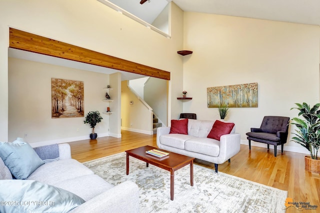 living area featuring stairs, baseboards, wood finished floors, and a towering ceiling