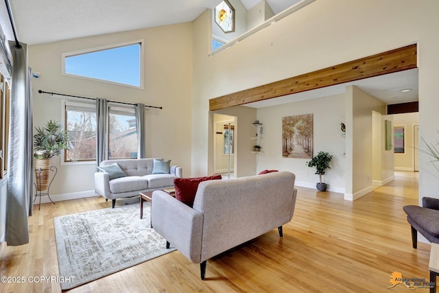 living room featuring light wood-type flooring, baseboards, and a high ceiling