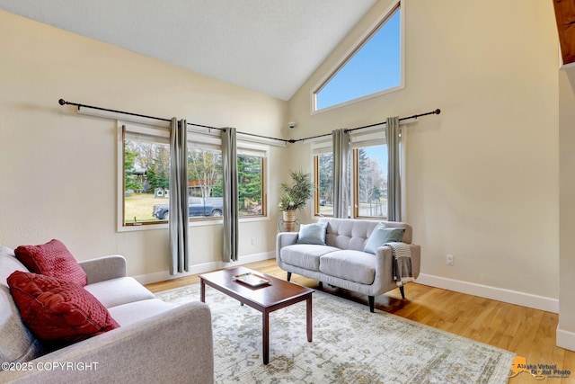 living room with baseboards, light wood finished floors, and high vaulted ceiling