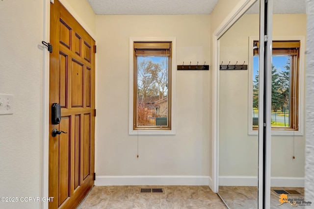 doorway to outside featuring baseboards, visible vents, and plenty of natural light