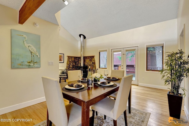 dining space featuring french doors, light wood-style flooring, a textured ceiling, and baseboards