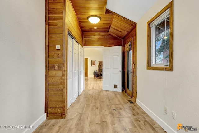 hallway featuring baseboards, vaulted ceiling, wood ceiling, and light wood-style flooring