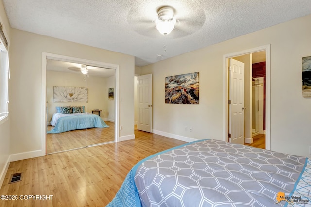 bedroom featuring a closet, visible vents, wood finished floors, baseboards, and a textured ceiling