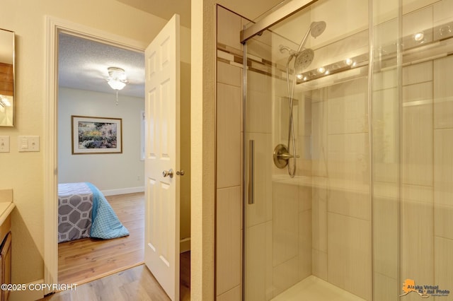 ensuite bathroom featuring vanity, wood finished floors, ensuite bathroom, a textured ceiling, and a stall shower