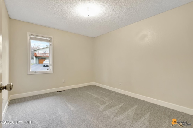 carpeted empty room featuring baseboards and a textured ceiling
