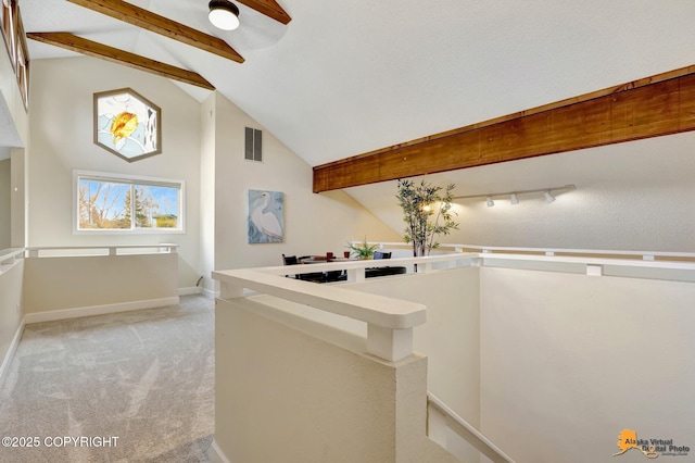 hallway with visible vents, baseboards, light colored carpet, lofted ceiling with beams, and an upstairs landing