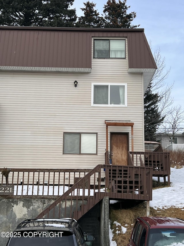 snow covered rear of property with a deck