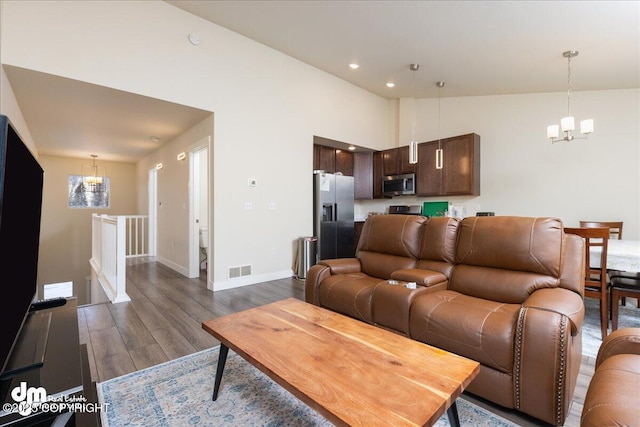 living room featuring dark hardwood / wood-style flooring, high vaulted ceiling, and an inviting chandelier