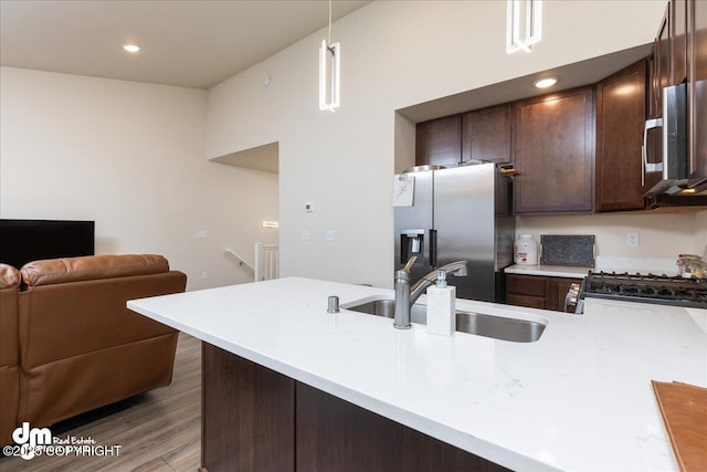 kitchen with dark brown cabinetry, sink, hanging light fixtures, appliances with stainless steel finishes, and kitchen peninsula