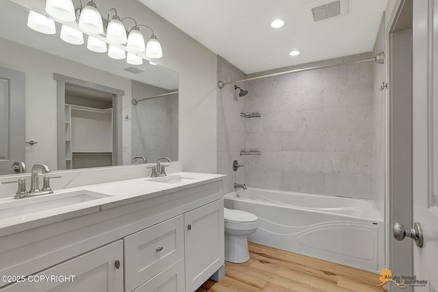 full bathroom with vanity, toilet, tiled shower / bath combo, and hardwood / wood-style floors