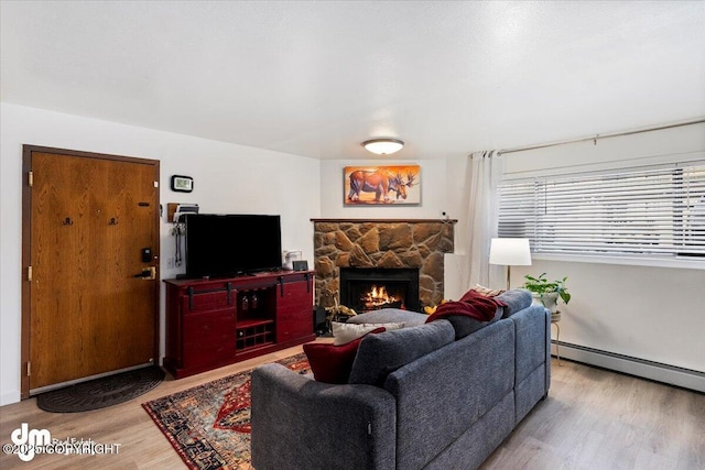 living room featuring wood-type flooring, a fireplace, and a baseboard heating unit